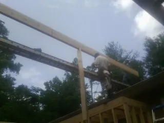 Carpenter setting a ridge beam over a new addition frame — Ice Dam Removal by Roofing Brothers in Marble Rock