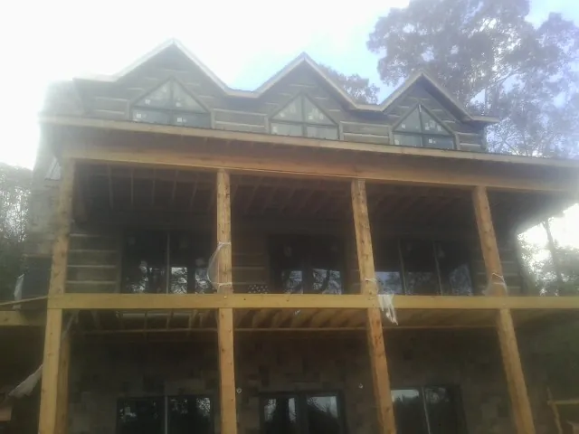 Dormers and porch framing on a large log home under construction — Roof Coating work by our crew in Marble Rock