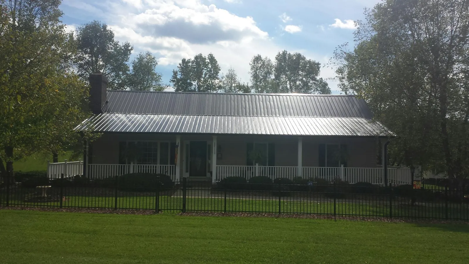 Gray metal roof on a brick ranch with a full width front porch — Gutter Guard Installation work by our crew in Marble Rock