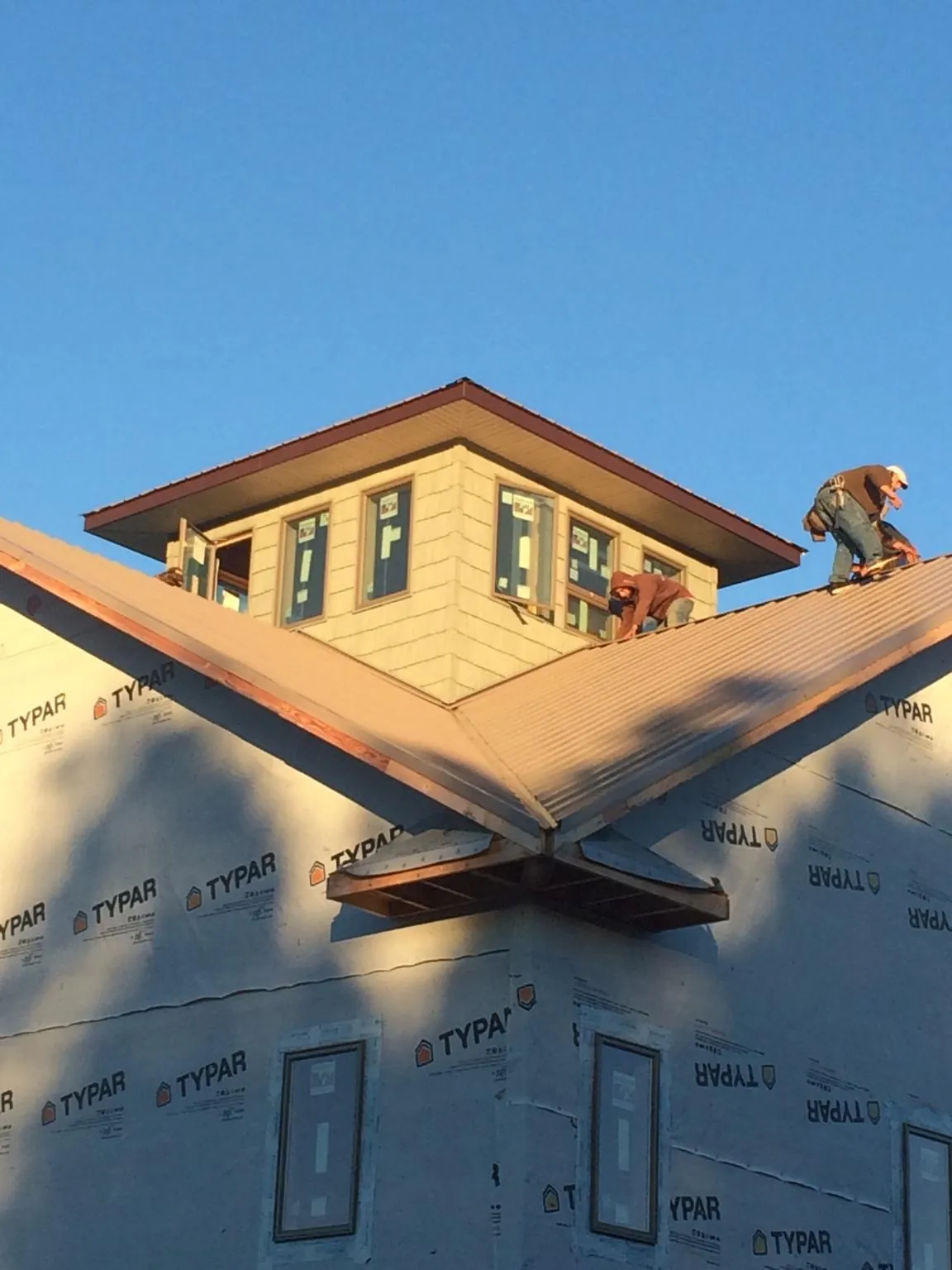Roofers working around a rooftop cupola on a new metal roof at sunset — Roof Waterproofing in Marble Rock by Roofing Brothers